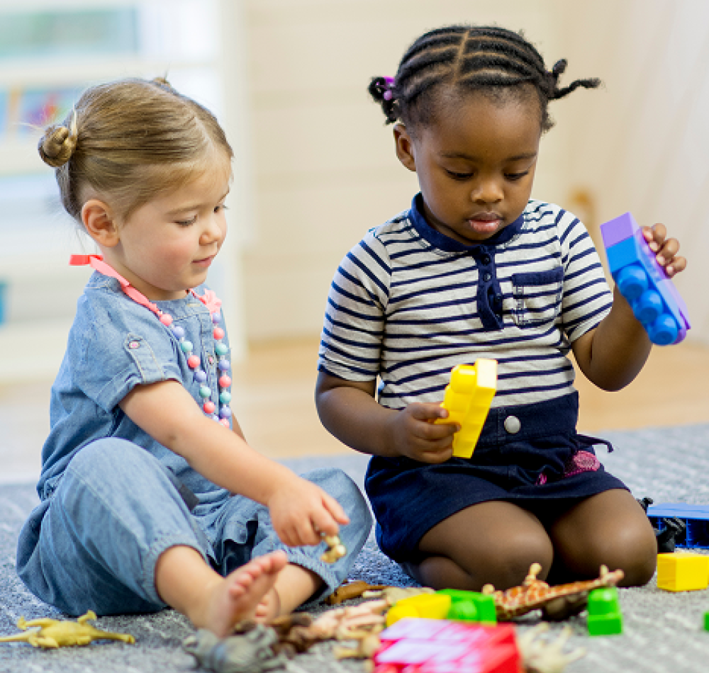 Two little girls playing with building blocks sat on the floor