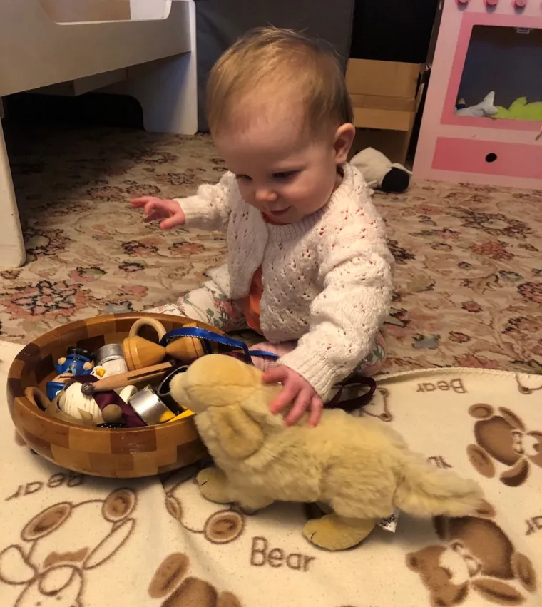 happy baby stroking toy dog