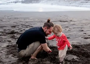 Child and man on beach playing