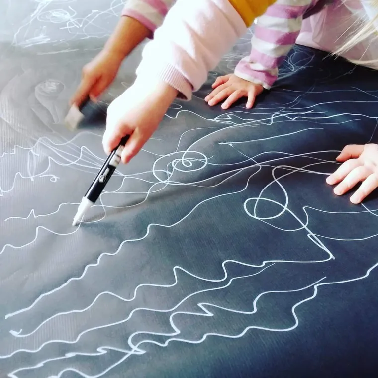 Close up photo of childrens hands mark-making on poster paper