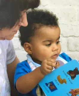 Infant reading a book with adult