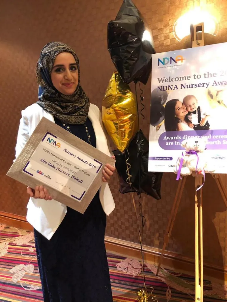 Woman with headscarf holding an award certifcate