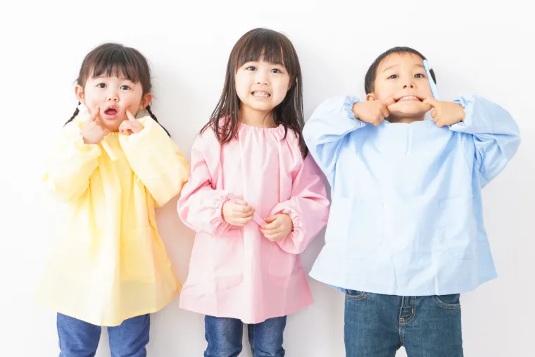 Three young children showing their teeth