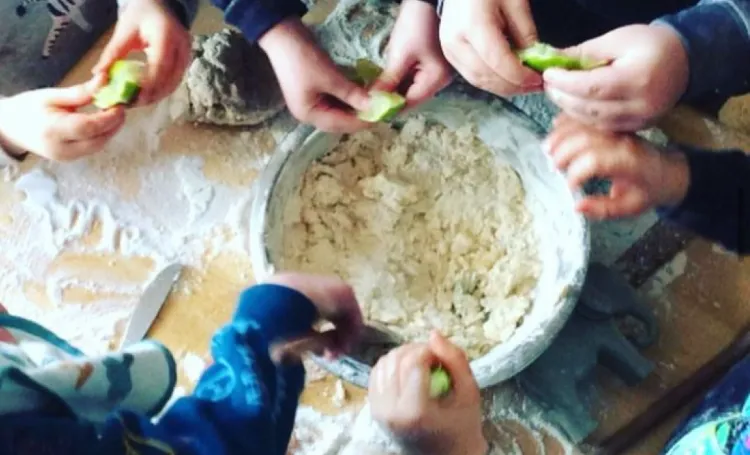 Children’s arms reaching into a bowl making playdough