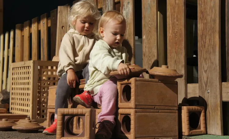 Children playing outdoors with wooden blocks