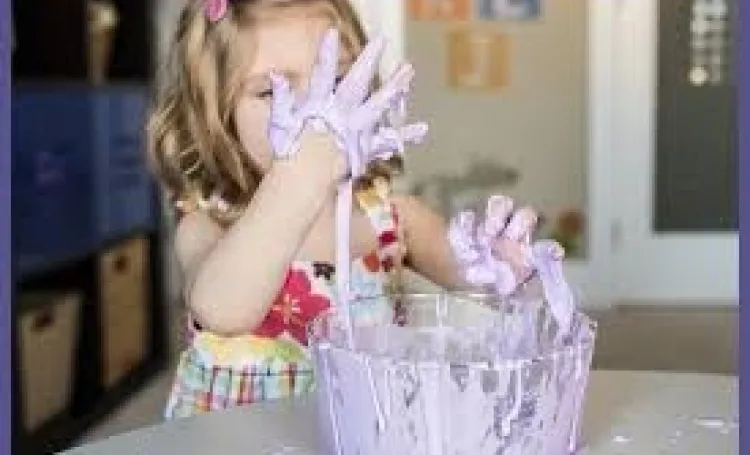 An early years child with her hands in a sticky substance in a bowl