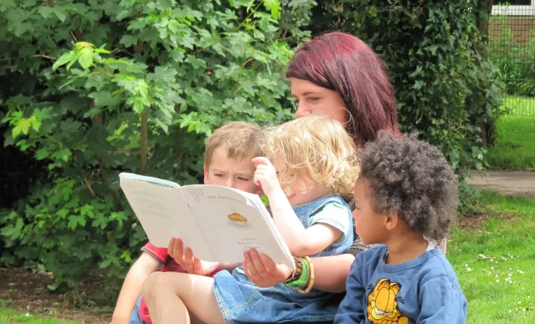 Early Years educator reading with two children