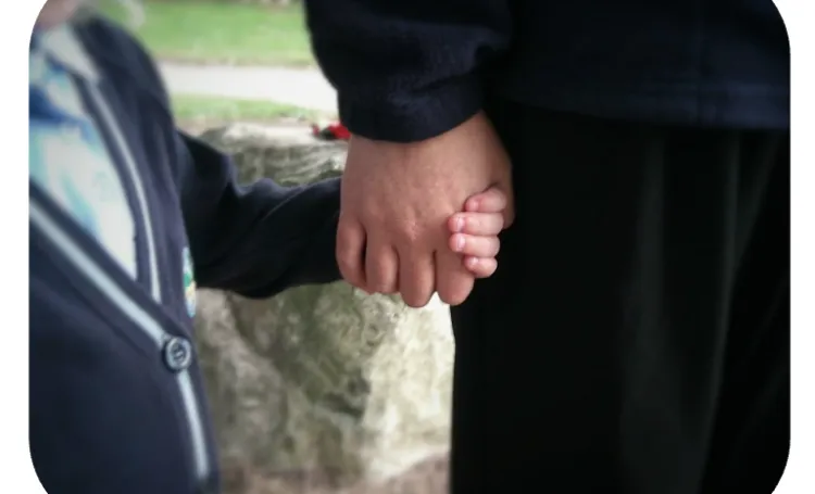 Child and adult holding hand for support