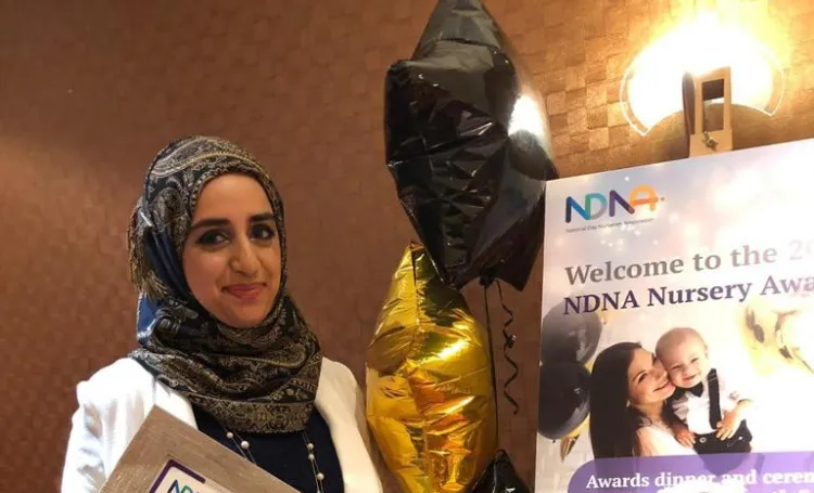 Woman with headscarf holding an award certifcate