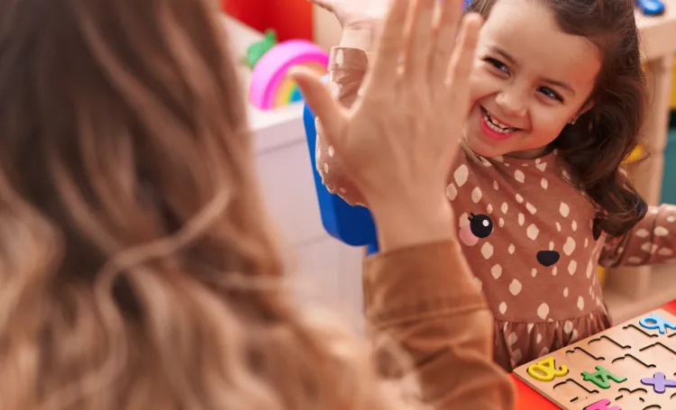 Child facing camera high-fiving an adult 