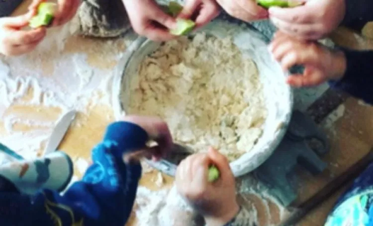 Children's hands mixing playdough in a large bowl 