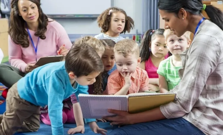 Children reading a book with two early years practitioners
