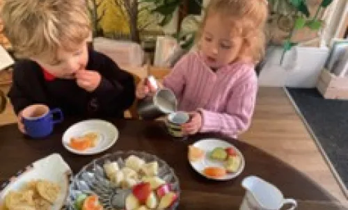 Two children in nursery enjoying a healthy snack together